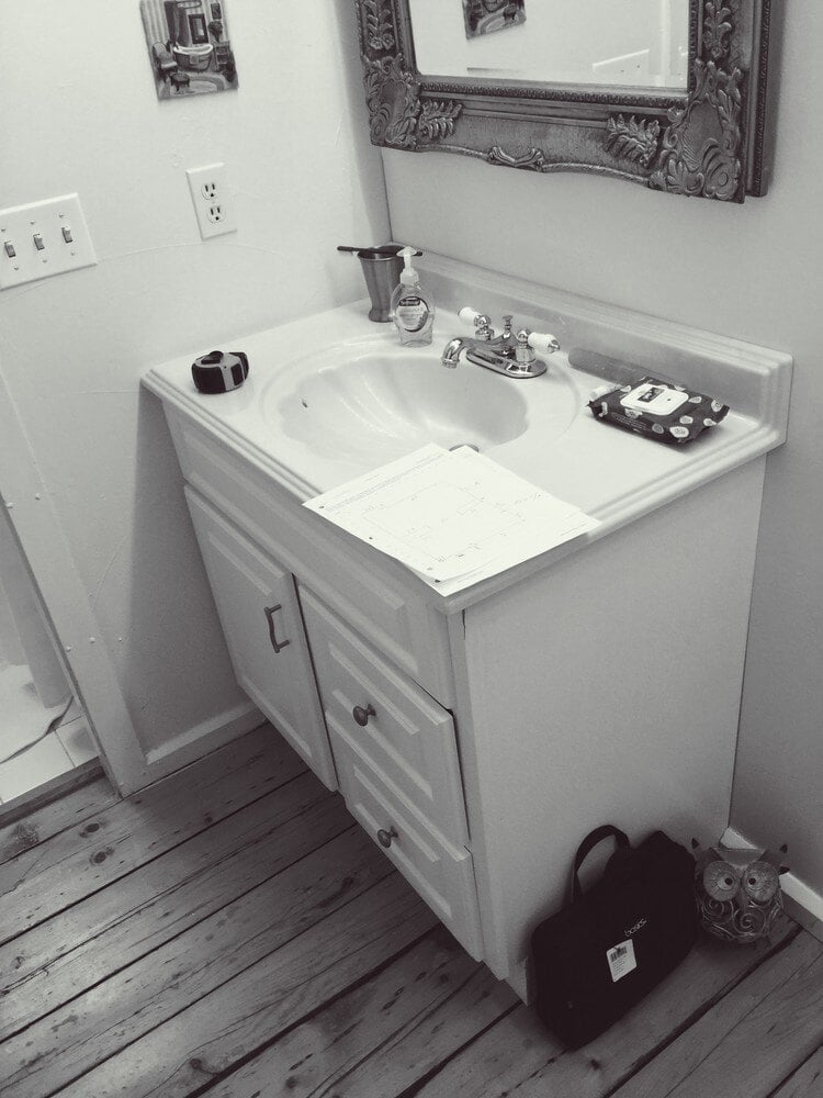 Before photo of a New Seabury bathroom with a small vanity and mirror, part of At Design Remodel project