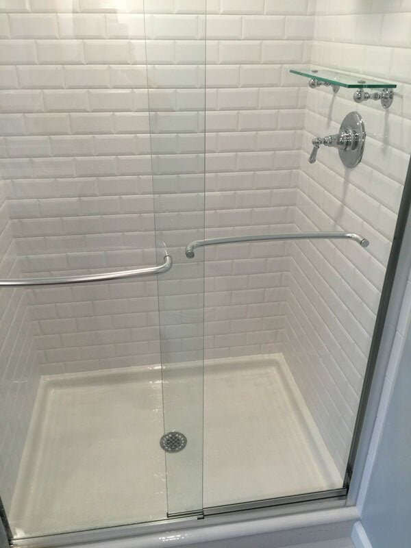 Glass-enclosed shower with white subway tiles in a Mashpee bathroom remodel by At Design Remodel