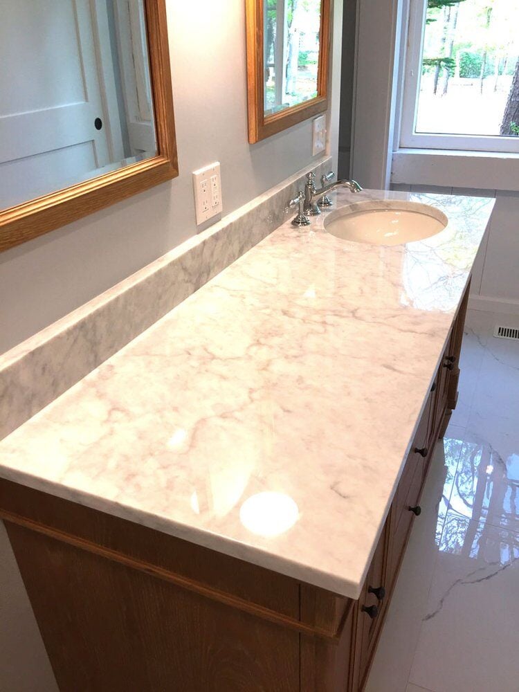 Marble countertop with wooden vanity in a Mashpee bathroom remodel by At Design Remodel