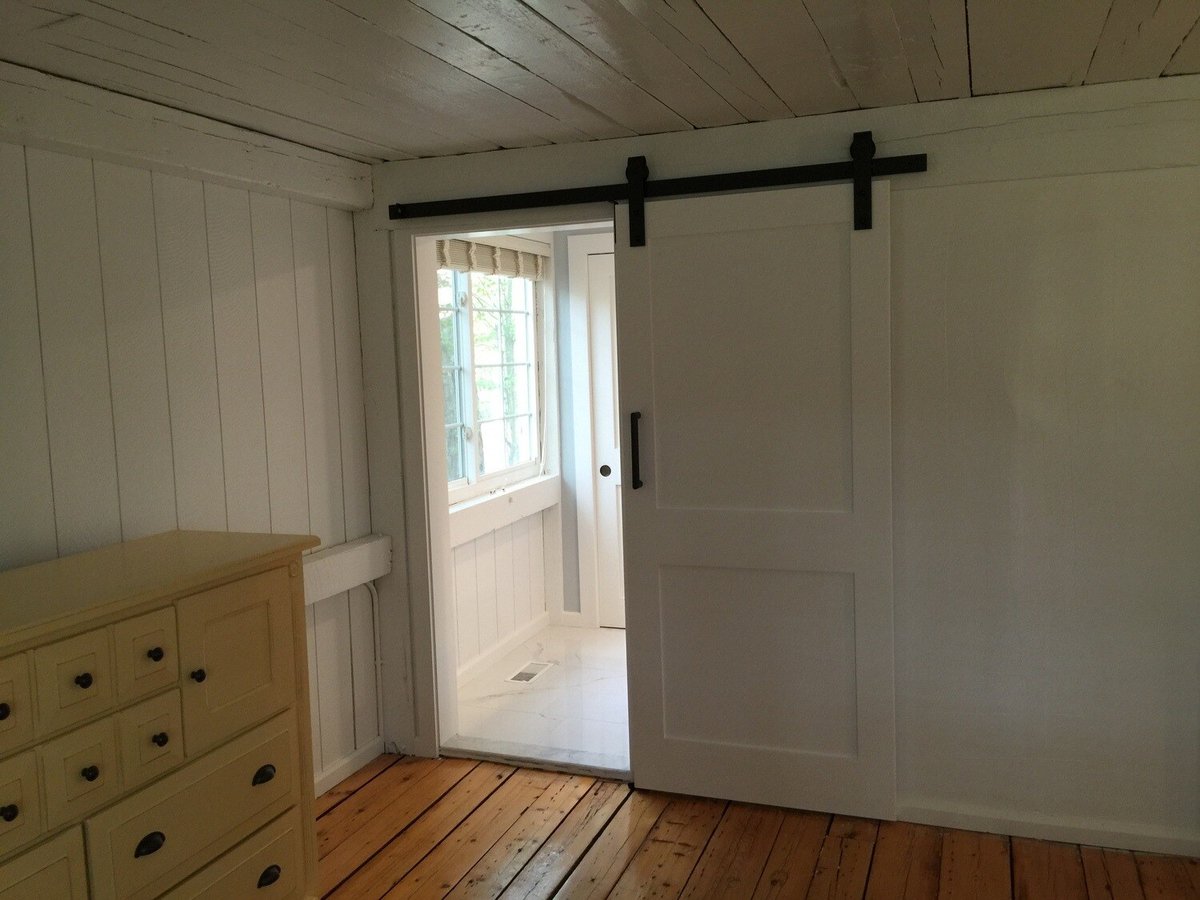 Remodeled bedroom with sliding door leading into a bathroom, Mashpee project by At Design Remodel