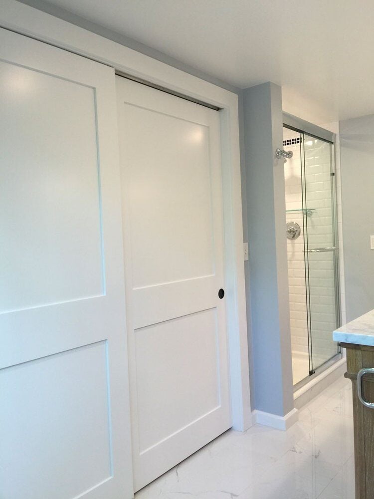 Sliding closet doors in a remodeled bathroom by At Design Remodel in Mashpee