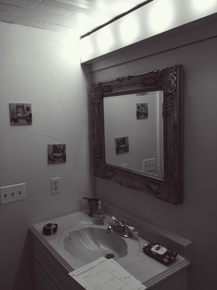Vanity with ornate mirror in a remodeled bathroom by At Design Remodel in Mashpee