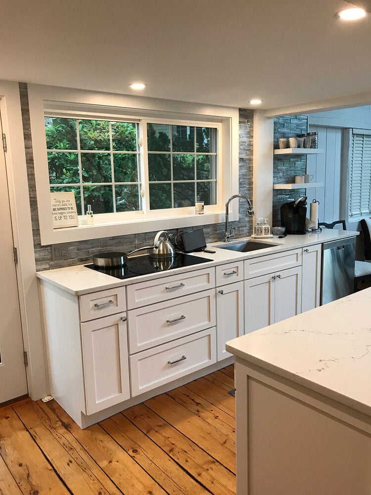 Kitchen remodel with white cabinets, wooden floors, and stainless steel appliances in a New Seabury home