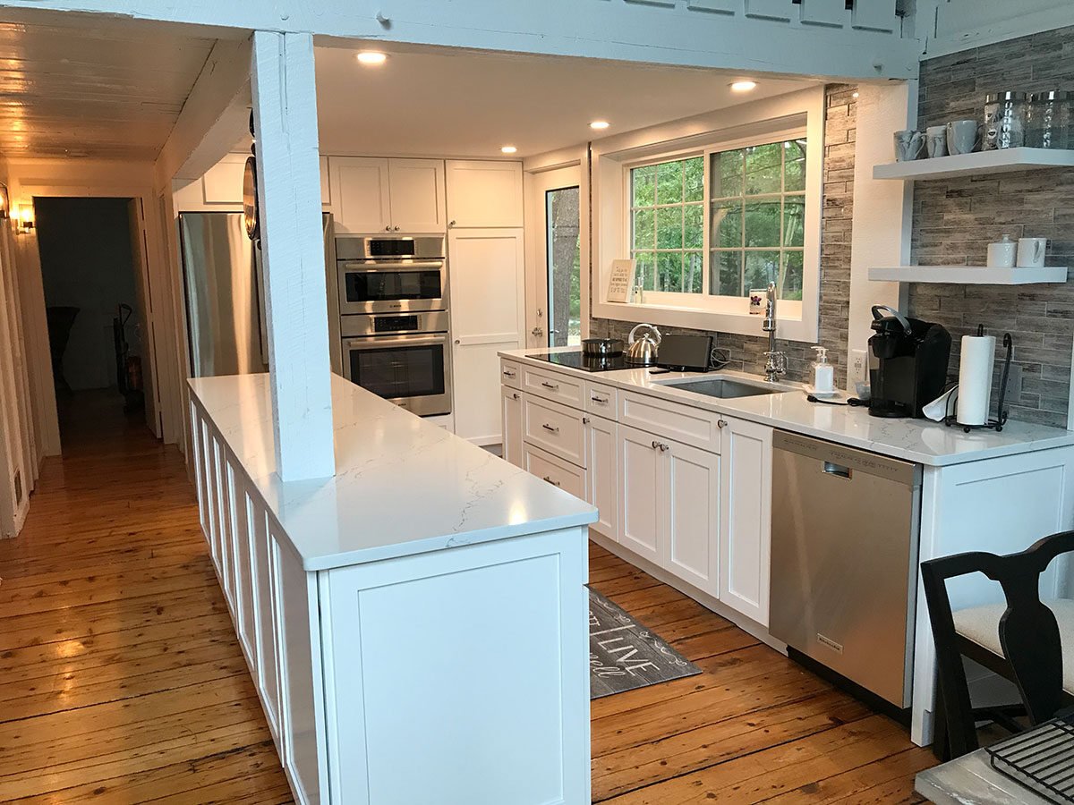 Sleek kitchen remodel with white cabinetry, stainless steel appliances, and large center island in Mashpee home