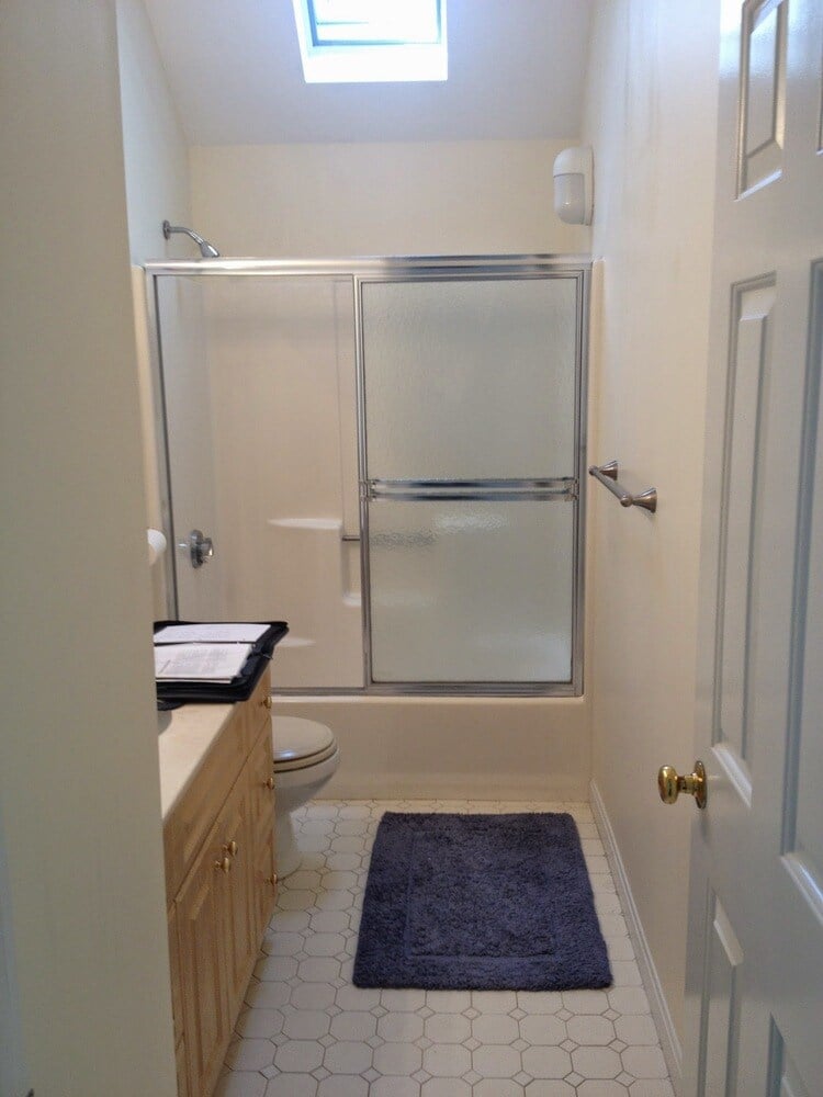 Bathroom with glass shower and overhead skylight in New Seabury Mews condo, remodeled by At Design Remodel