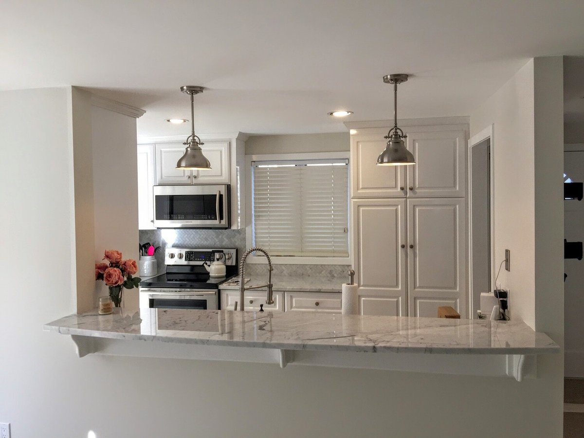 Bright and airy living room with white sofas and large windows in New Seabury Mews condo, remodeled by At Design Remodel