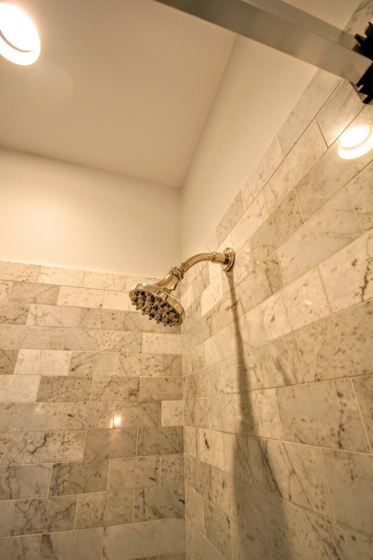 Polished marble shower with rainfall showerhead in New Seabury Mews condo, remodeled by At Design Remodel