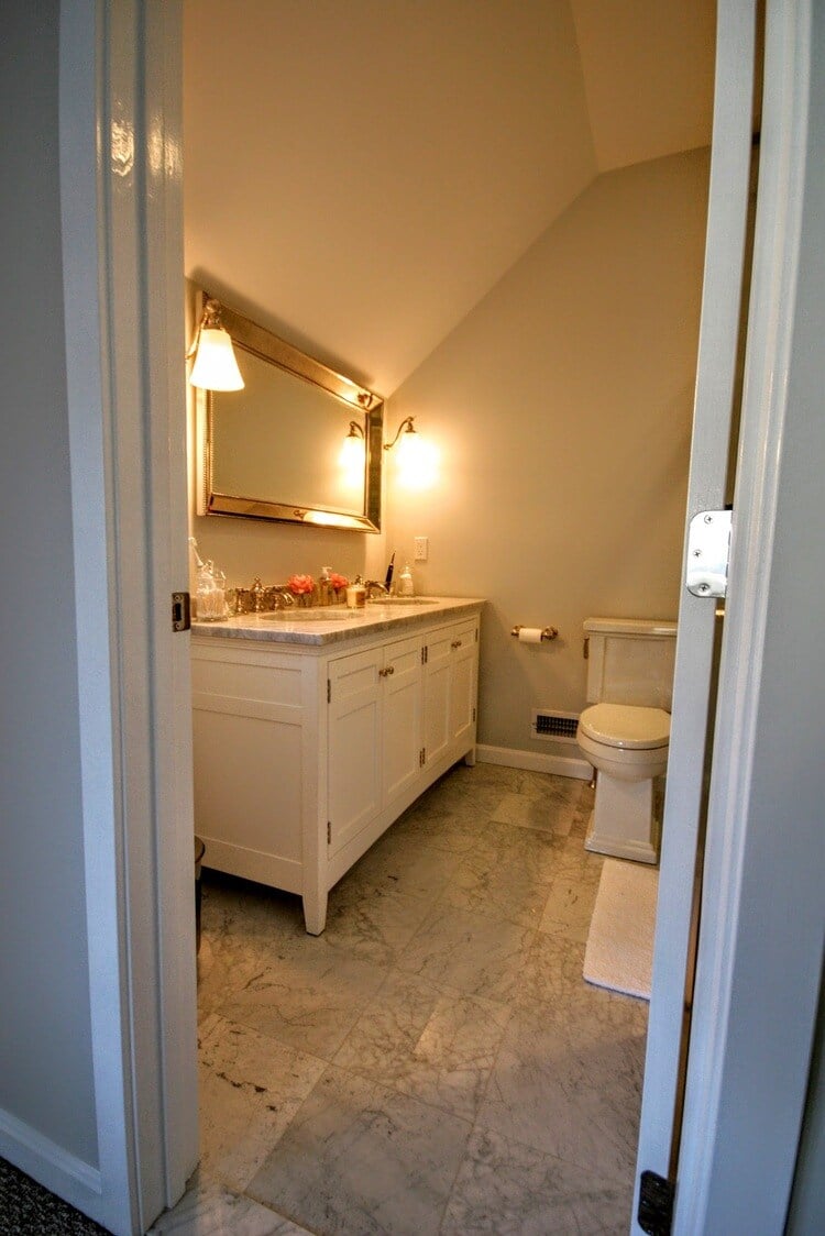 Powder room with marble flooring and a large vanity mirror in New Seabury Mews condo, remodeled by At Design Remodel