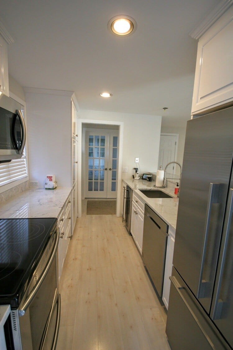 Sleek marble island with built-in sink and faucet in New Seabury Mews condo kitchen, remodeled by At Design Remodel