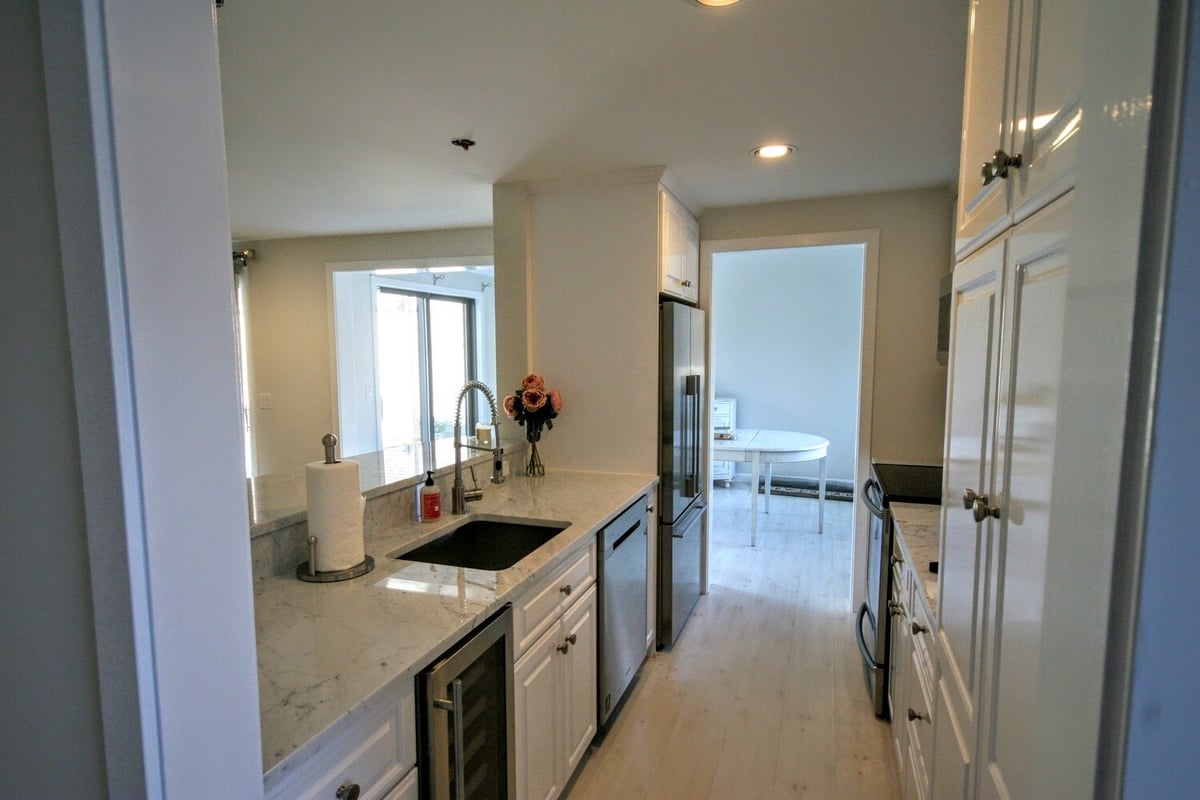 Updated kitchen featuring marble countertops and stainless steel appliances, part of New Seabury Mews condo remodel by At Design Remodel