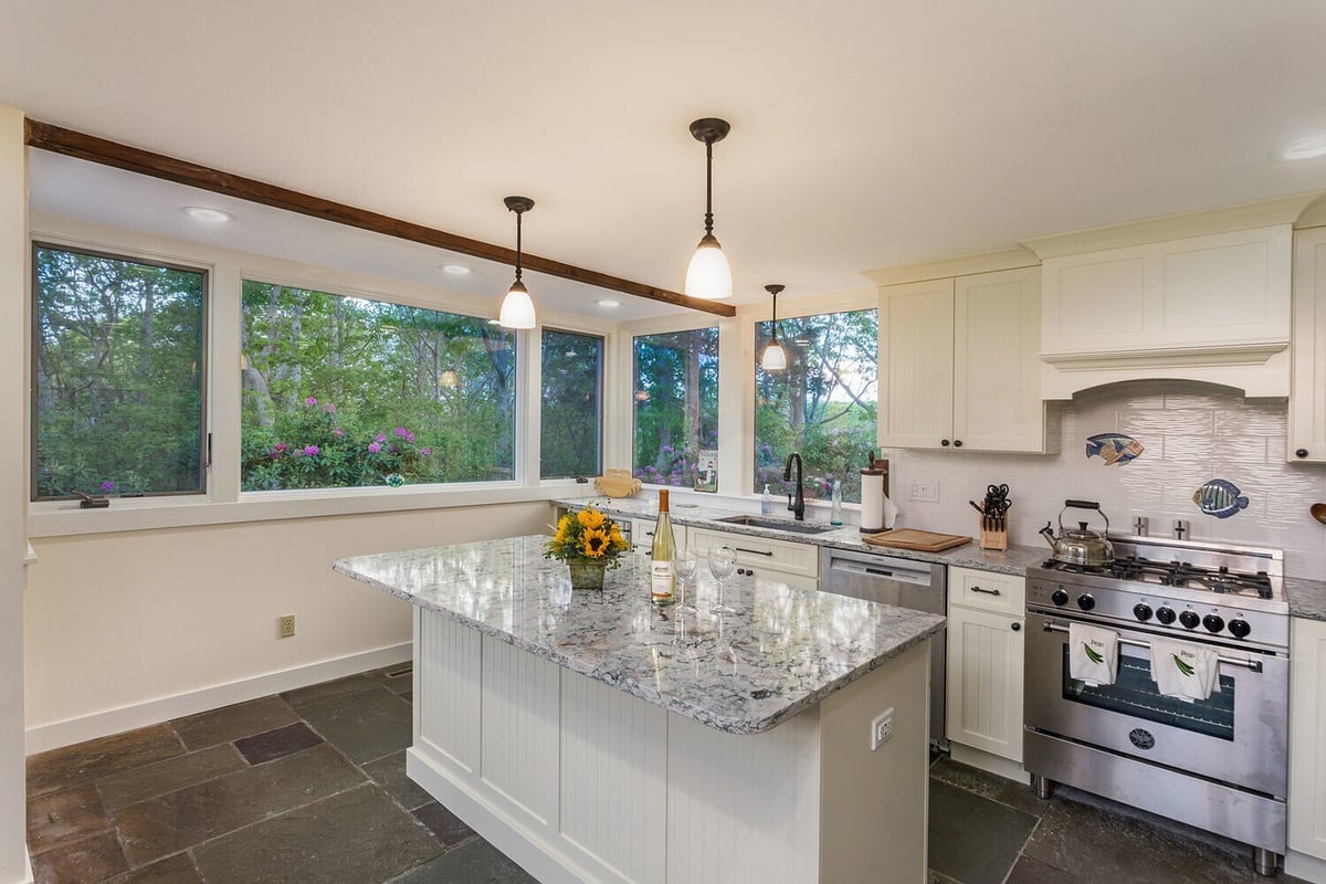 Bright kitchen remodel with a large island and scenic outdoor views, designed in North Falmouth
