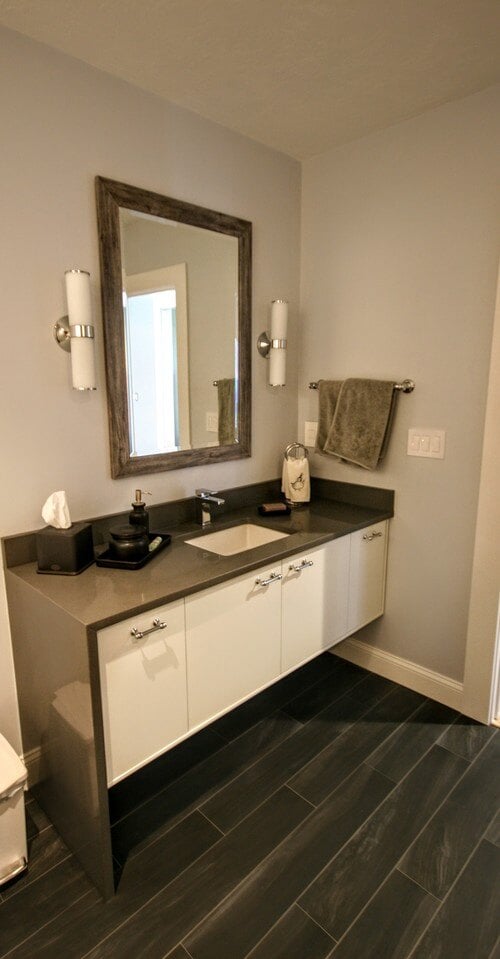 Bathroom vanity featuring gray countertop and framed mirror, part of a custom home renovation by At Design Remodel in Mashpee