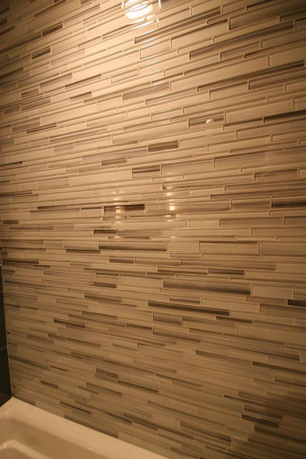 Custom tiled shower wall with a mix of neutral tones, part of a bathroom remodel in Mashpee by At Design Remodel