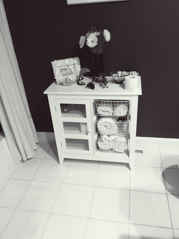 Small bathroom cabinet with storage baskets and decor, designed by At Design Remodel in Mashpee, MA