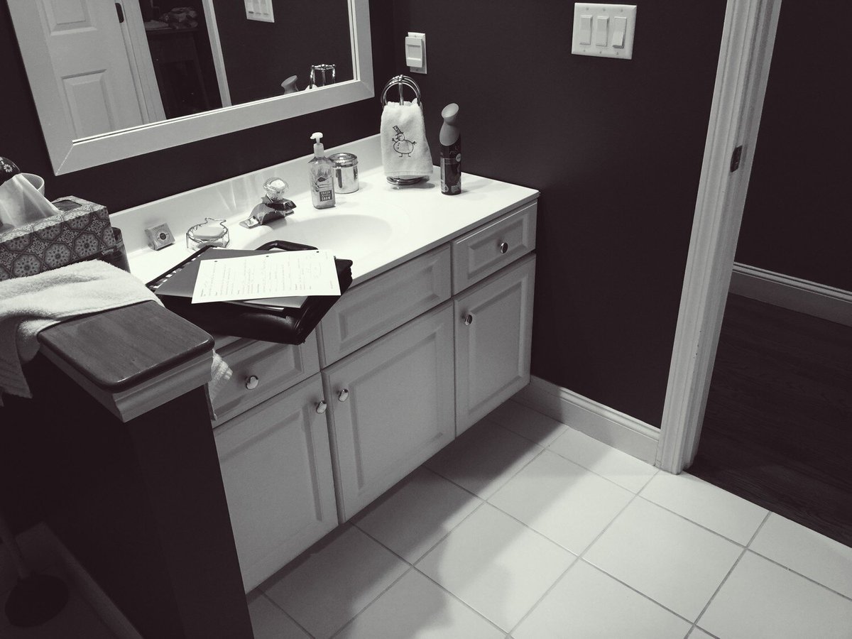 White bathroom vanity with toiletries and papers, designed by At Design Remodel in a Mashpee home renovation