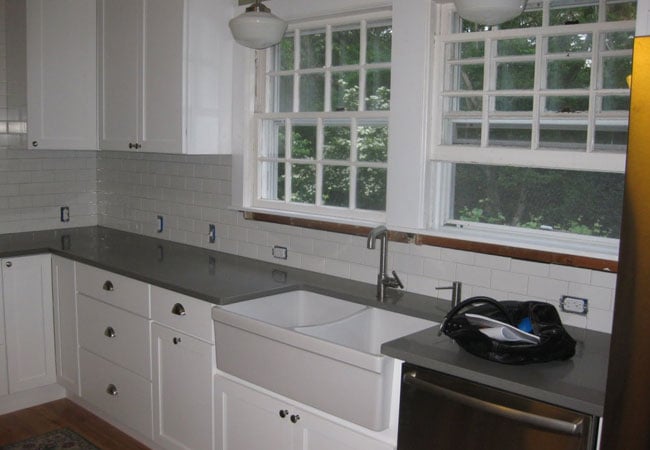 Completed kitchen with white cabinets and dark countertops in a West Falmouth remodel by At Design Remodel, Mashpee