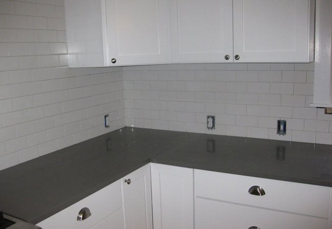 Dark granite countertops and white cabinetry in a remodeled West Falmouth kitchen by At Design Remodel