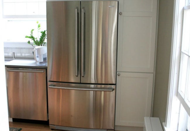 Large stainless steel fridge next to white cabinetry in a remodeled West Falmouth kitchen by At Design Remodel