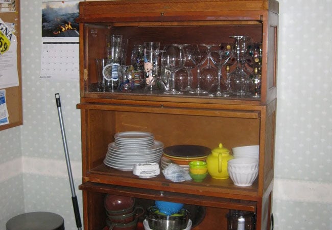 Wooden display cabinet with glassware and dishes in a West Falmouth kitchen remodel by At Design Remodel, Mashpee