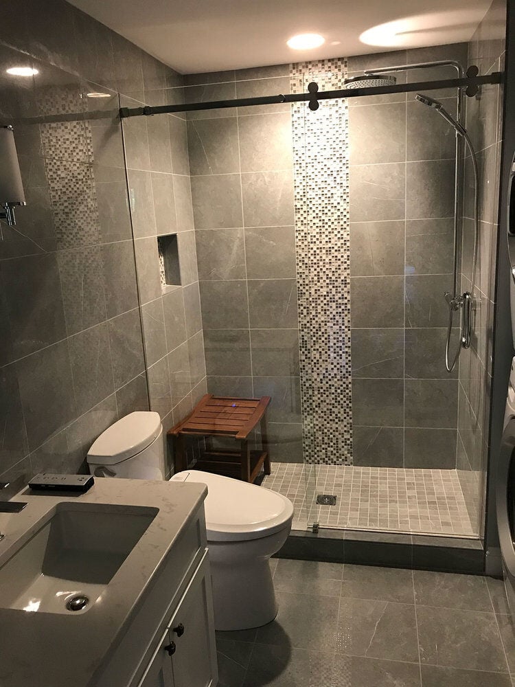 Full view of bathroom with glass-enclosed shower and dual sink vanity in a Yarmouthport remodel by At Design Remodel