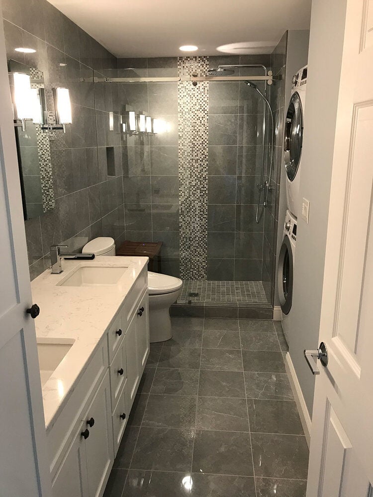 Long view of bathroom featuring glass shower and washer-dryer setup in a Yarmouthport remodel by At Design Remodel