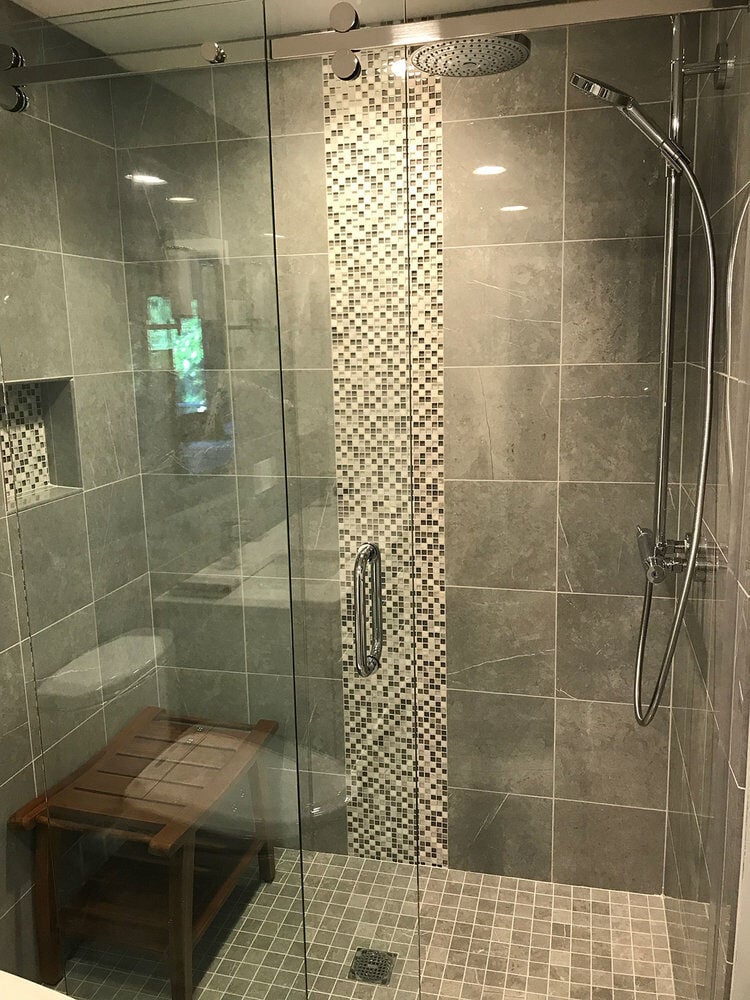 Shower with gray tiles and mosaic accent wall in a Yarmouthport bathroom remodel by At Design Remodel