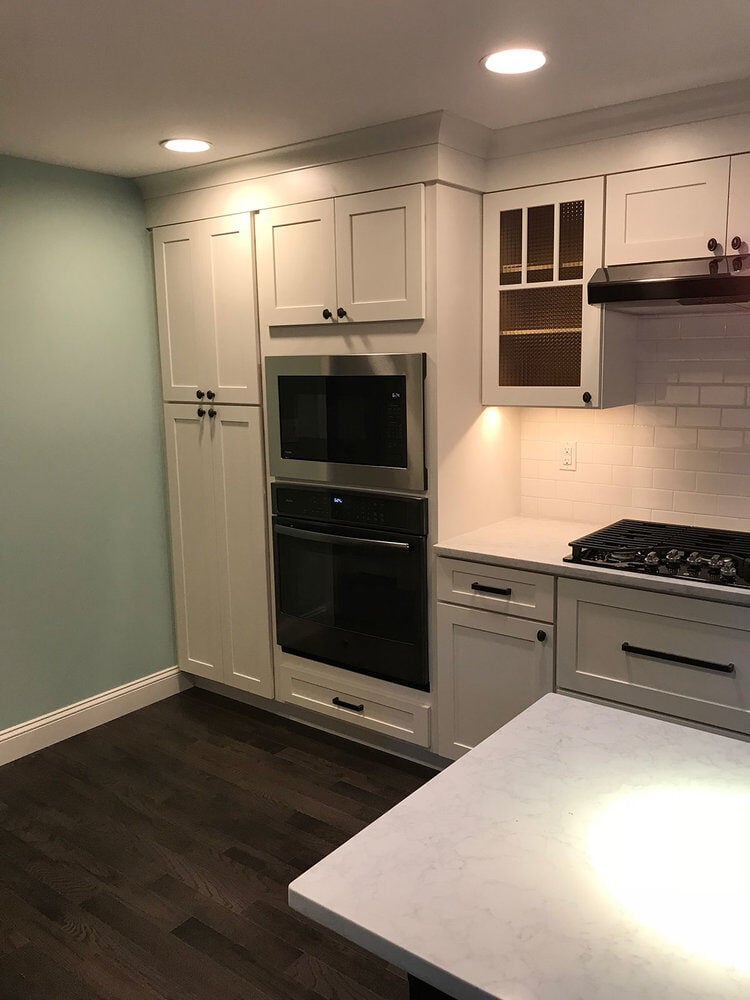 Close-up of sleek white cabinetry and built-in oven in Yarmouthport kitchen remodel by At Design Remodel, Mashpee