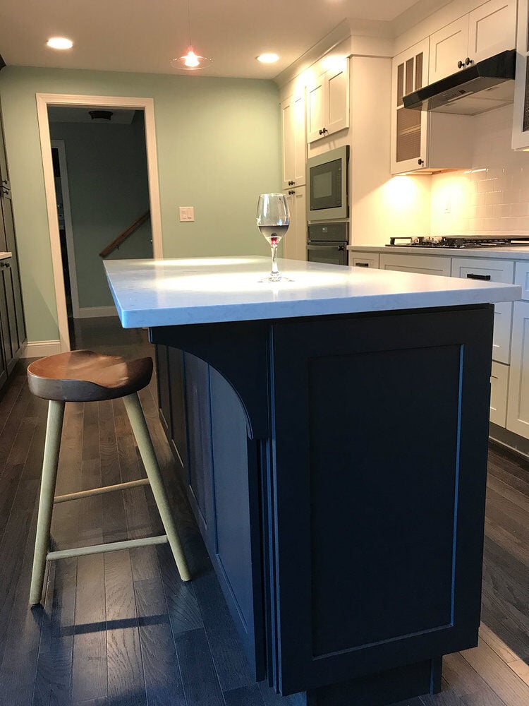 Dark wood kitchen island with a sleek white surface in a remodeled Yarmouthport kitchen by At Design Remodel, Mashpee