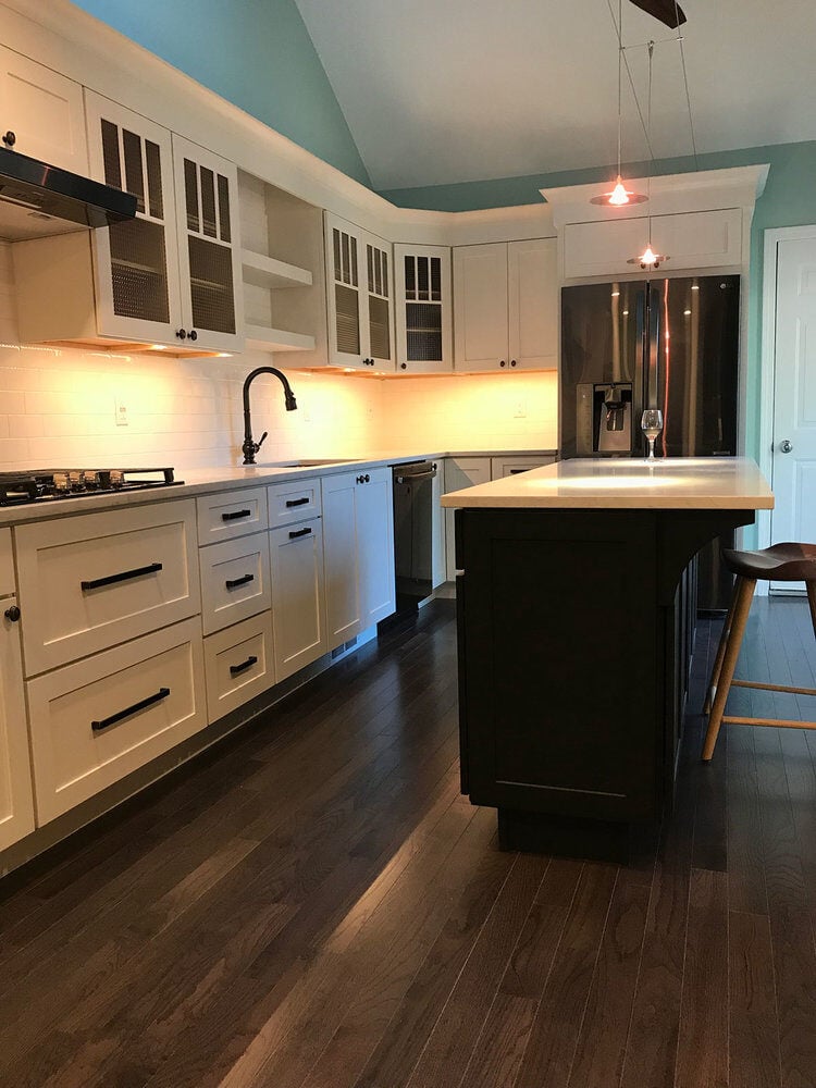 Open-concept kitchen with white cabinets and dark island in Yarmouthport by At Design Remodel, Mashpee